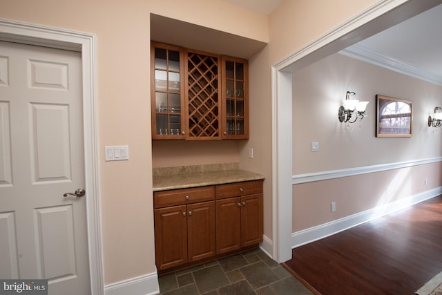 bar featuring light stone countertops, dark hardwood / wood-style flooring, and ornamental molding