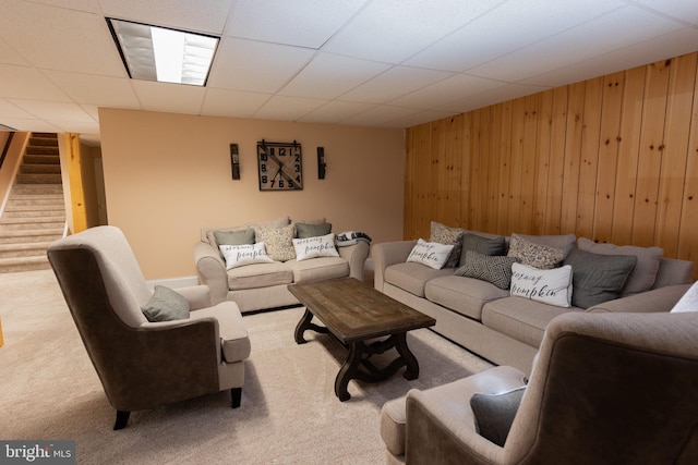 carpeted living room with a paneled ceiling and wooden walls