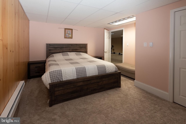 bedroom featuring a paneled ceiling, wooden walls, carpet floors, and a baseboard radiator