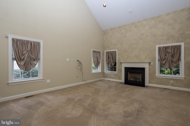 unfurnished living room with high vaulted ceiling and light colored carpet