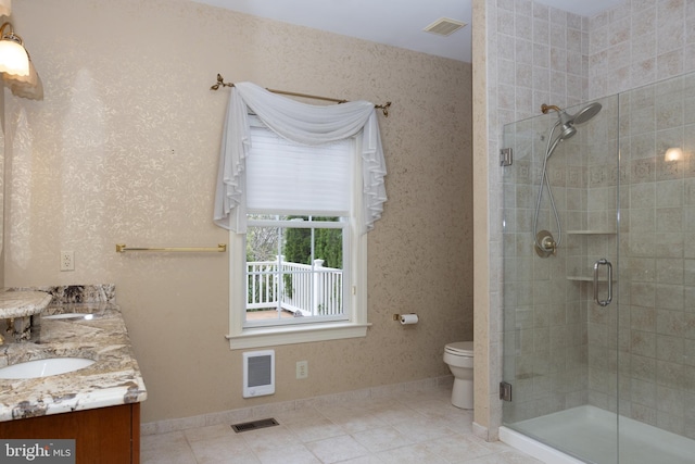 bathroom with heating unit, a shower with shower door, vanity, tile patterned flooring, and toilet