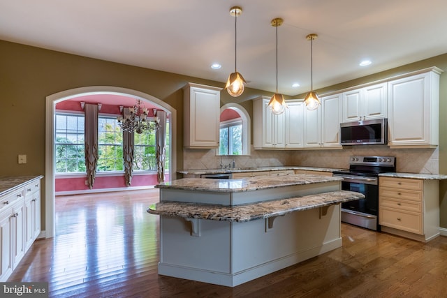 kitchen featuring white cabinets, appliances with stainless steel finishes, hardwood / wood-style floors, and tasteful backsplash