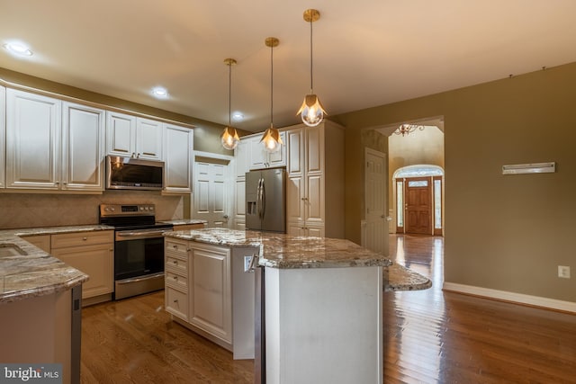 kitchen featuring hanging light fixtures, a kitchen island, backsplash, stainless steel appliances, and dark hardwood / wood-style floors