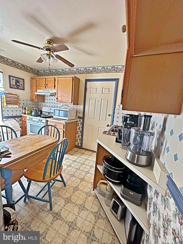 kitchen with ceiling fan, white range with gas stovetop, and backsplash