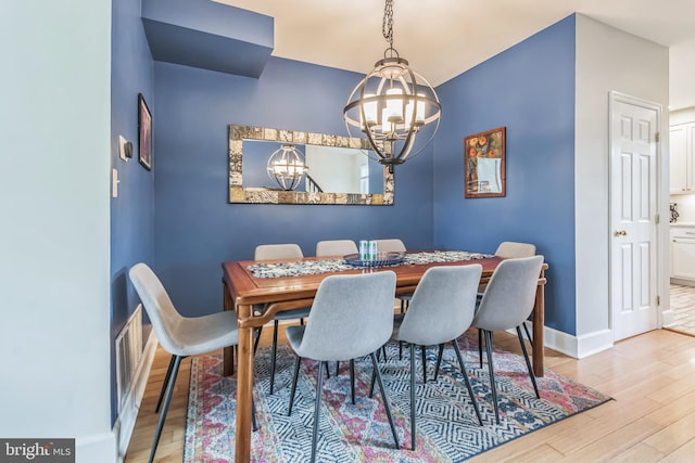 dining space featuring light wood-type flooring and a chandelier