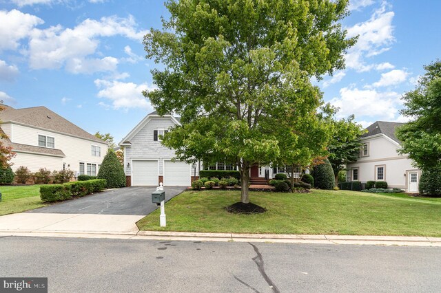 view of property hidden behind natural elements with a garage and a front lawn