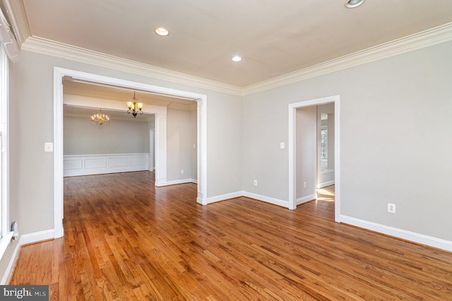 empty room with ornamental molding, wood-type flooring, and a chandelier