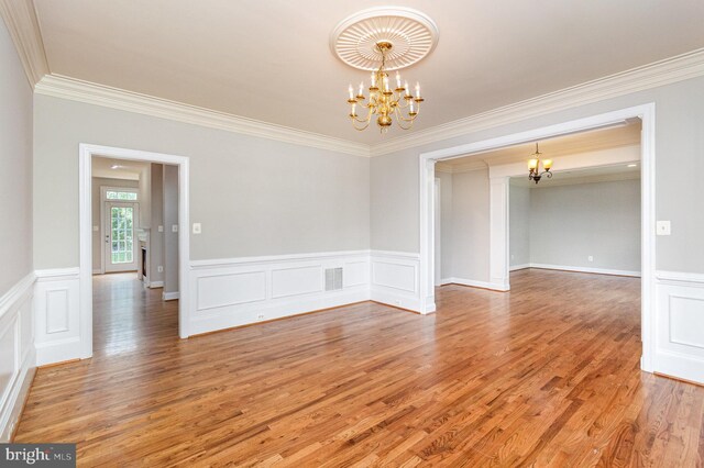 unfurnished room with crown molding, hardwood / wood-style floors, and a chandelier