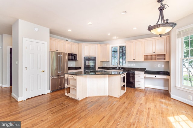 kitchen with light hardwood / wood-style flooring, black appliances, a kitchen island, and a healthy amount of sunlight