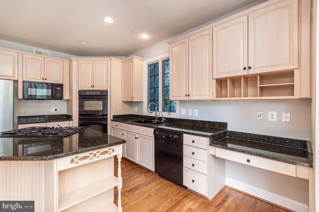 kitchen with light wood-type flooring, sink, dark stone counters, and black appliances