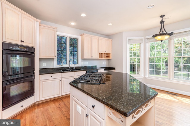 kitchen with pendant lighting, light wood-type flooring, black appliances, dark stone counters, and sink