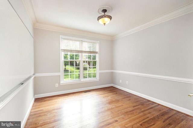 spare room featuring ornamental molding and light hardwood / wood-style floors