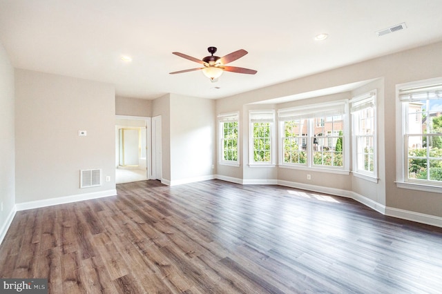 unfurnished living room featuring dark wood-type flooring, ceiling fan, and a wealth of natural light