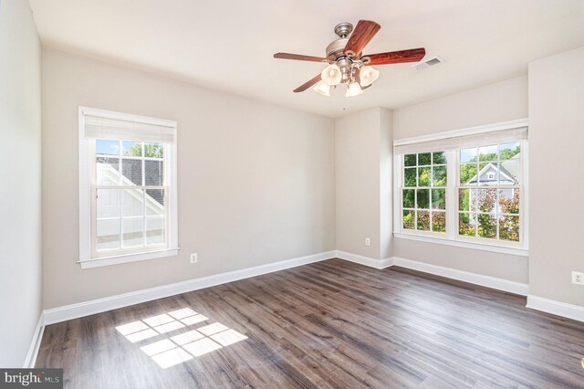 unfurnished room featuring a healthy amount of sunlight, dark hardwood / wood-style flooring, and ceiling fan