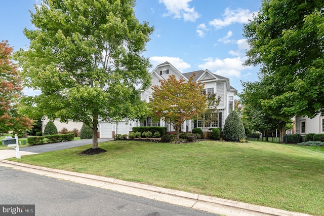 view of property hidden behind natural elements with a front yard and a garage