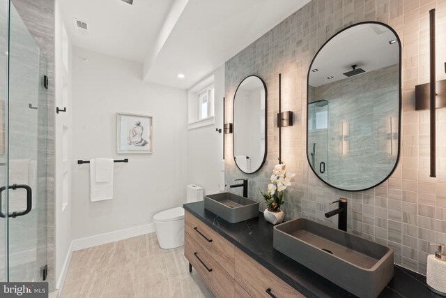 bathroom with tile walls, a shower with door, and toilet