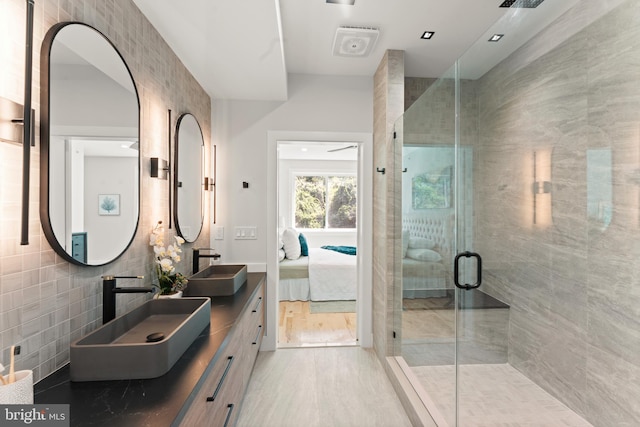 bathroom with tile walls, hardwood / wood-style floors, a shower with shower door, and vanity