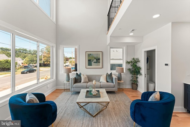 living room with light wood-type flooring and a high ceiling