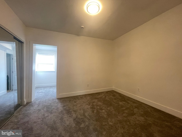 spare room featuring dark carpet