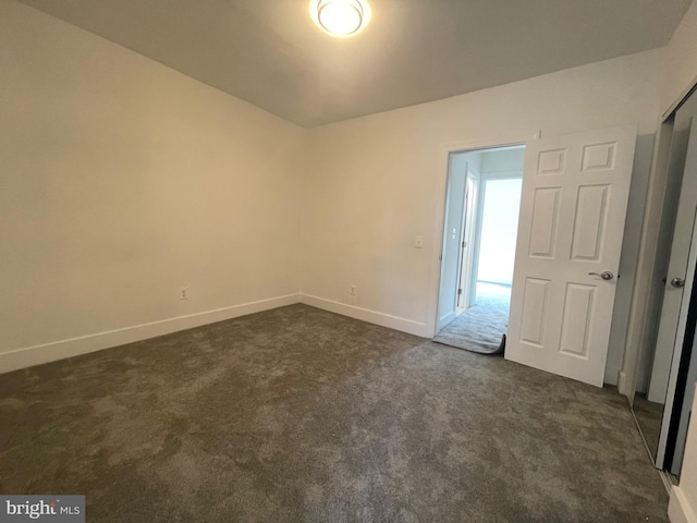 unfurnished bedroom featuring dark carpet and a closet