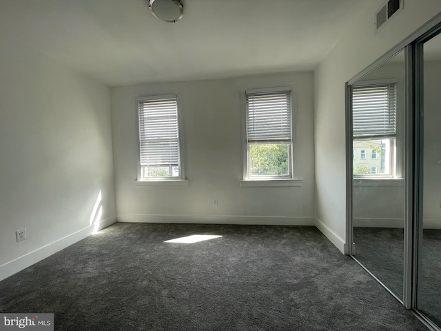 unfurnished bedroom with a closet and dark colored carpet