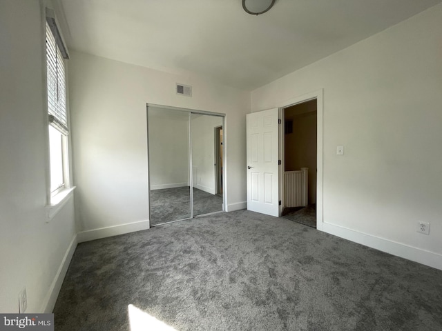 unfurnished bedroom featuring dark carpet and a closet