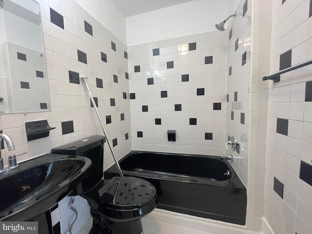 full bathroom featuring tile walls, backsplash, tiled shower / bath combo, toilet, and sink