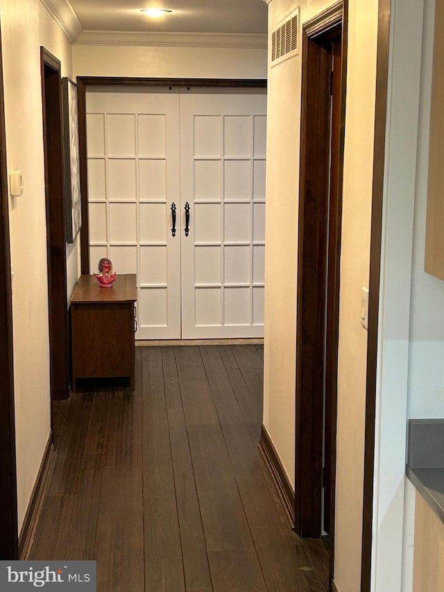 corridor with dark hardwood / wood-style floors and ornamental molding