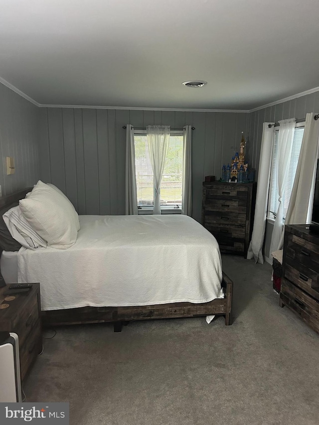 carpeted bedroom with wooden walls and ornamental molding