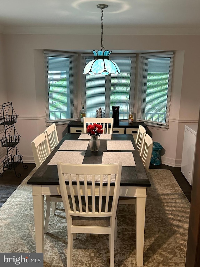 dining space featuring crown molding, washer / dryer, and dark wood-type flooring