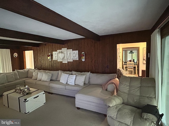 carpeted living room featuring wooden walls and beam ceiling