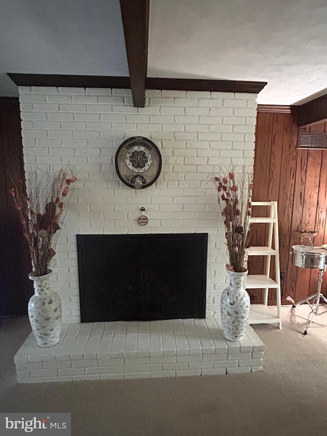 details with a brick fireplace, beam ceiling, wood walls, and carpet flooring