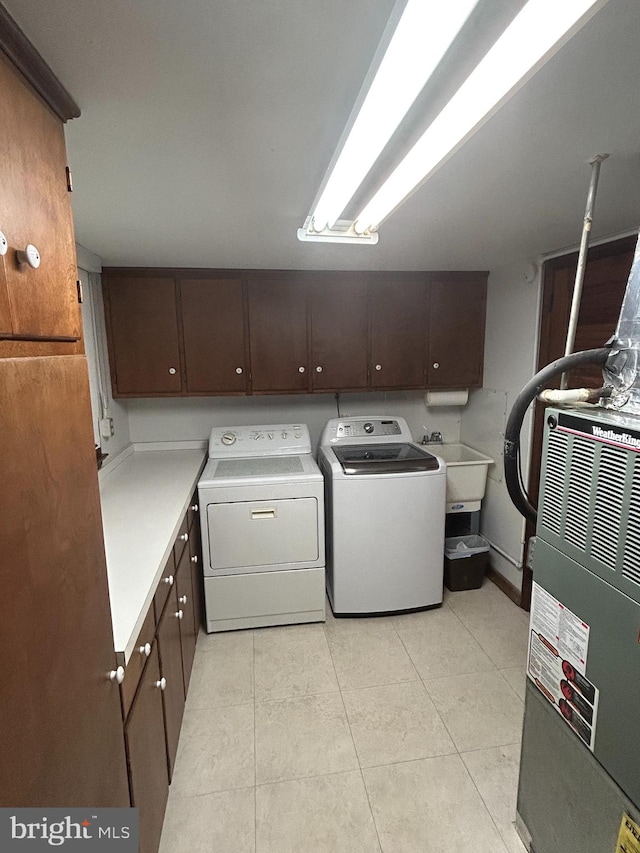 clothes washing area featuring cabinets, light tile patterned floors, washer and dryer, and sink