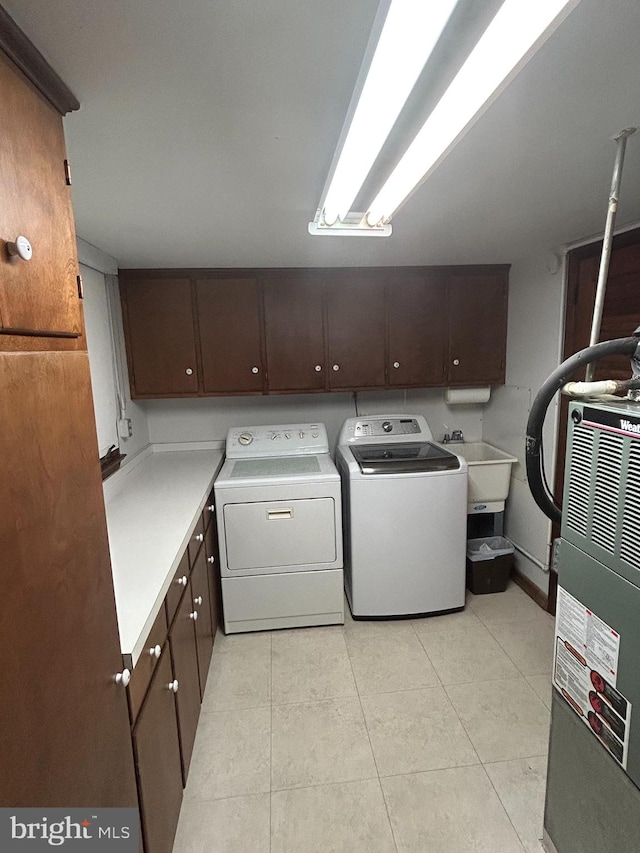 washroom with washing machine and dryer, light tile patterned flooring, heating unit, cabinets, and sink