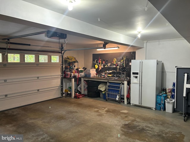 garage featuring a garage door opener, a workshop area, and white refrigerator with ice dispenser