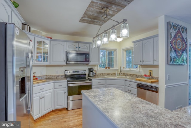 kitchen featuring pendant lighting, light hardwood / wood-style floors, sink, white cabinetry, and appliances with stainless steel finishes