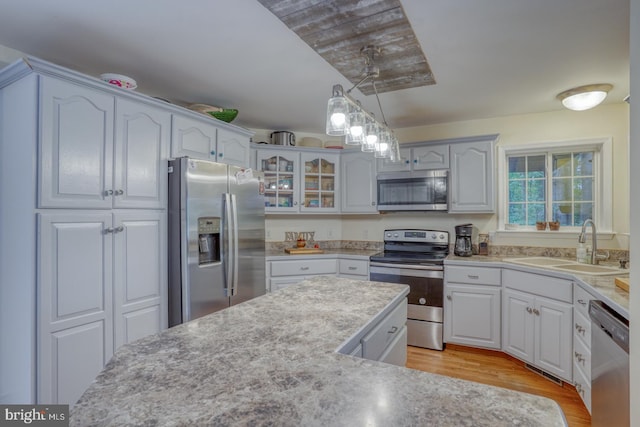 kitchen featuring light wood-type flooring, sink, stainless steel appliances, and white cabinets