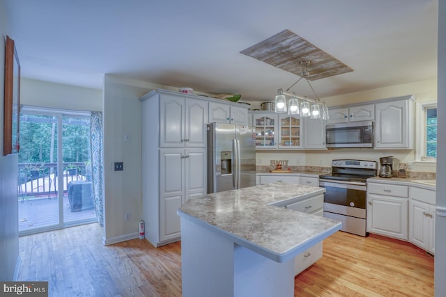 kitchen with a healthy amount of sunlight, stainless steel appliances, decorative light fixtures, and a kitchen island