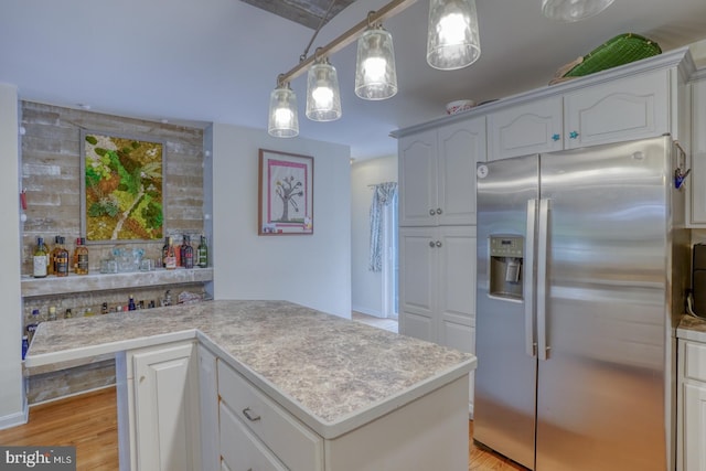 kitchen featuring white cabinets, hanging light fixtures, stainless steel fridge with ice dispenser, a center island, and light wood-type flooring