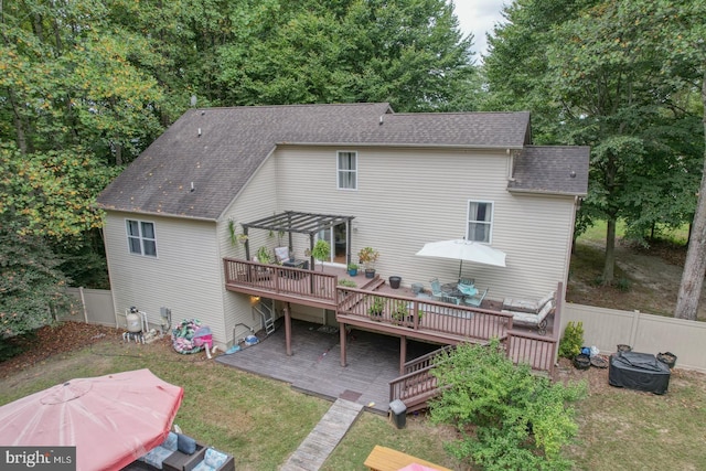 rear view of house with a wooden deck and a lawn