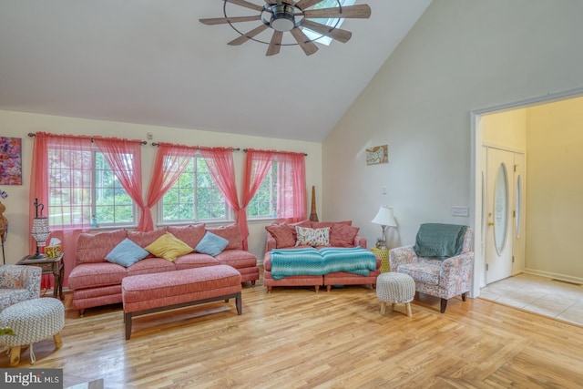 living room with high vaulted ceiling, ceiling fan, and light hardwood / wood-style flooring