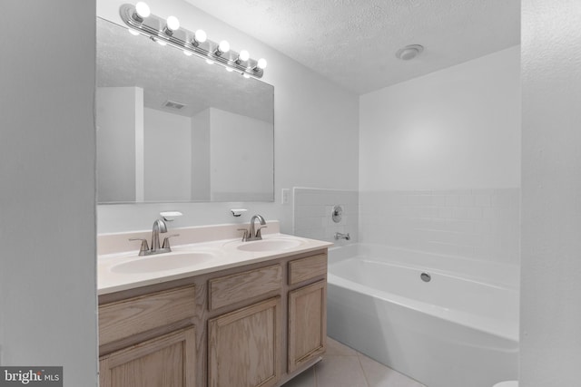 bathroom featuring vanity, tile patterned flooring, a textured ceiling, and a bathtub