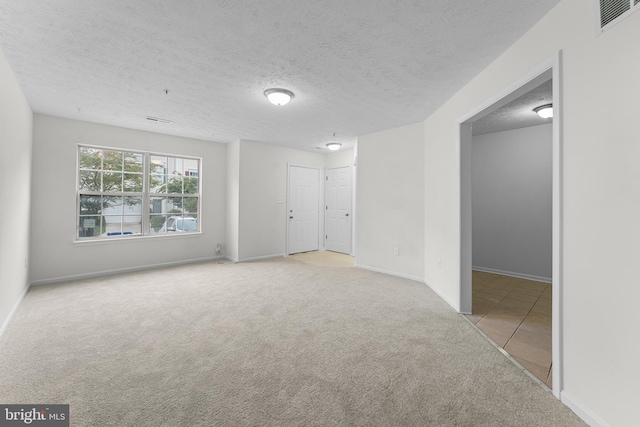 spare room featuring a textured ceiling and light colored carpet