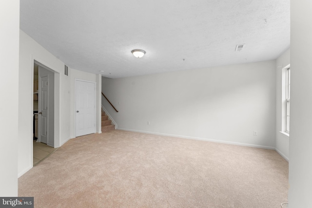 spare room with a textured ceiling and light colored carpet