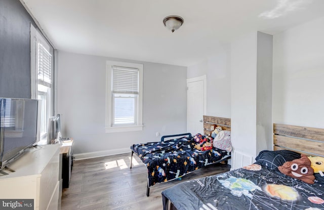 bedroom with multiple windows and light hardwood / wood-style flooring