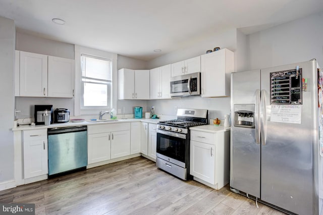 kitchen with stainless steel appliances, white cabinets, and light wood-type flooring