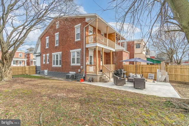 rear view of house featuring a lawn, a patio, outdoor lounge area, a balcony, and central AC unit