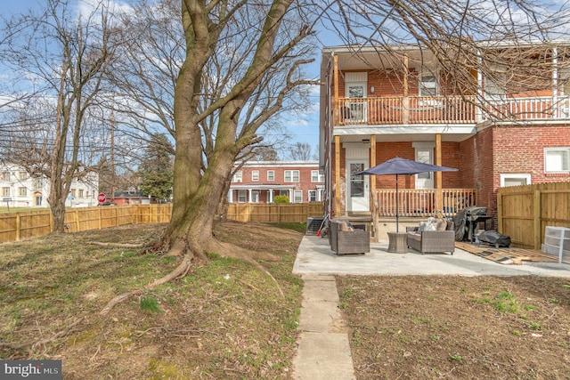 rear view of property with a balcony, a lawn, and a patio area