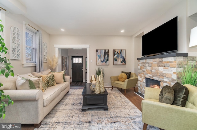 living room with a wealth of natural light, hardwood / wood-style floors, and a stone fireplace