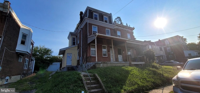 view of front of home with covered porch, brick siding, and mansard roof